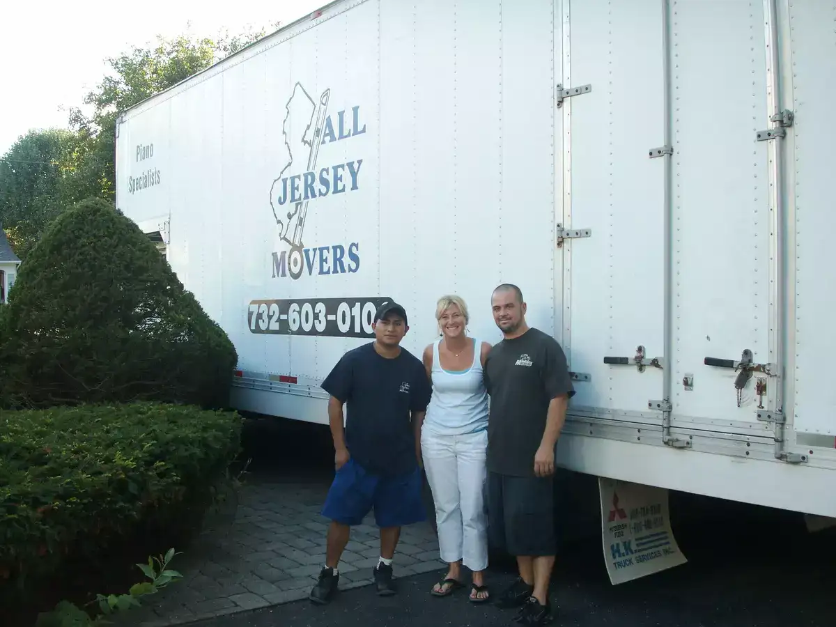 Two men and a woman standing in front of All Jersey Movers container truck
