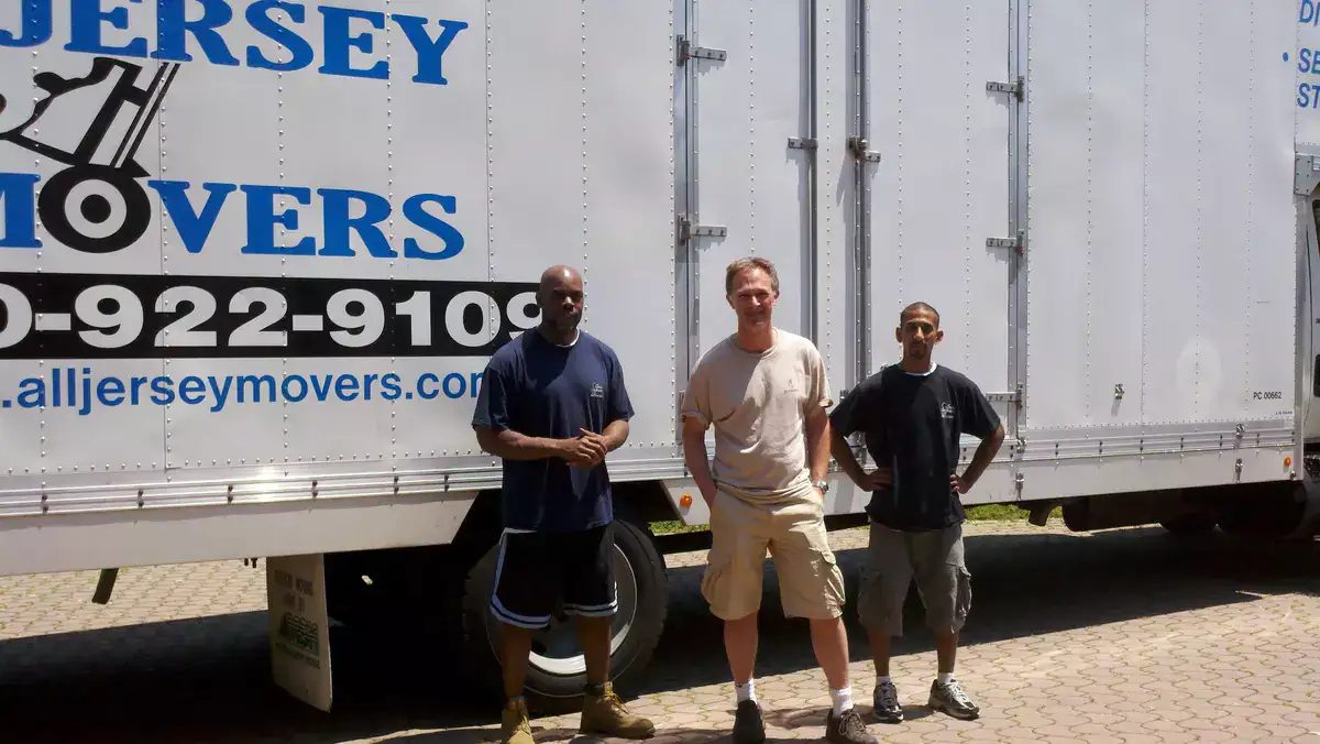 Two members of All Jersey Movers clicking a photo with a client after service