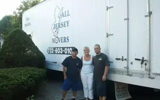 Two men and a woman standing in front of All Jersey Movers container truck