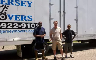 Two members of All Jersey Movers clicking a photo with a client after service